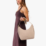Taupe Medium | Model holding u-shaped, flat-bottomed leather shoulder bag with adjustable strap