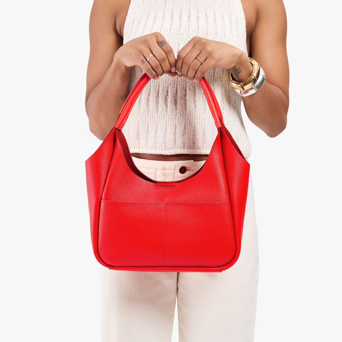 Candy*Medium | Model holding a u-shaped, flat-bottomed leather shoulder bag with two outside pockets