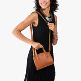 Honey Mini | Model carrying small leather tote bag with handles, adjustable crossbody strap, and one back pocket