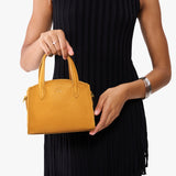 Sunshine Mini | Model carrying small leather tote bag with handles, adjustable crossbody strap, and one back pocket