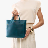 Westward Blue Classic | Model holding crossbody tote bag with snap closure and front pocket