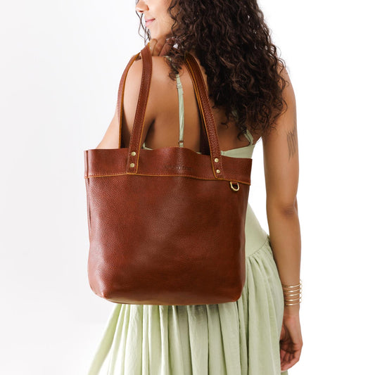 Nutmeg*Medium*Classic | Model wearing leather tote bag with riveted straps and exterior key loop