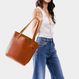 Sienna Medium Classic | Model holding a leather tote bag with riveted straps and exterior key loop