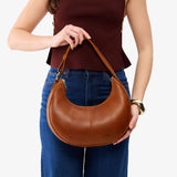 Honey Small | Model holding crescent shaped leather shoulder bag with zipper closure and adjustable strap