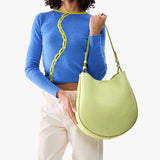 Shadow Lime Large | Model holding round leather purse with adjustable shoulder strap