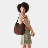 Stagecoach Large | Woman wearing rounded shoulder bag with adjustable strap on a white background