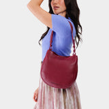 Orchid Medium | Woman wearing rounded shoulder bag with adjustable strap on a white background