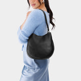 Pebbled--black Medium | Woman wearing rounded shoulder bag with adjustable strap on a white background