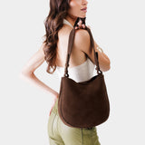 Stagecoach Medium | Woman wearing rounded shoulder bag with adjustable strap on a white background