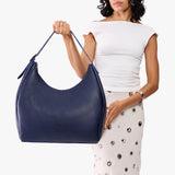 Cobalt Oversized | Model carrying U-shaped, flat-bottomed leather shoulder bag with adjustable strap