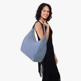 Denim Oversized | Model holding u-shaped, flat-bottomed leather shoulder bag with adjustable strap