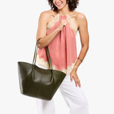 Model wearing sleeveless pink lace-trim top and white pants carrying an Oversized Devan Bucket Tote in Pebbled Olive