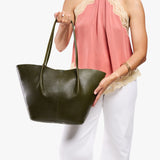 Model wearing sleeveless pink lace-trim top and white pants carrying an Oversized Devan Bucket Tote in Pebbled Olive