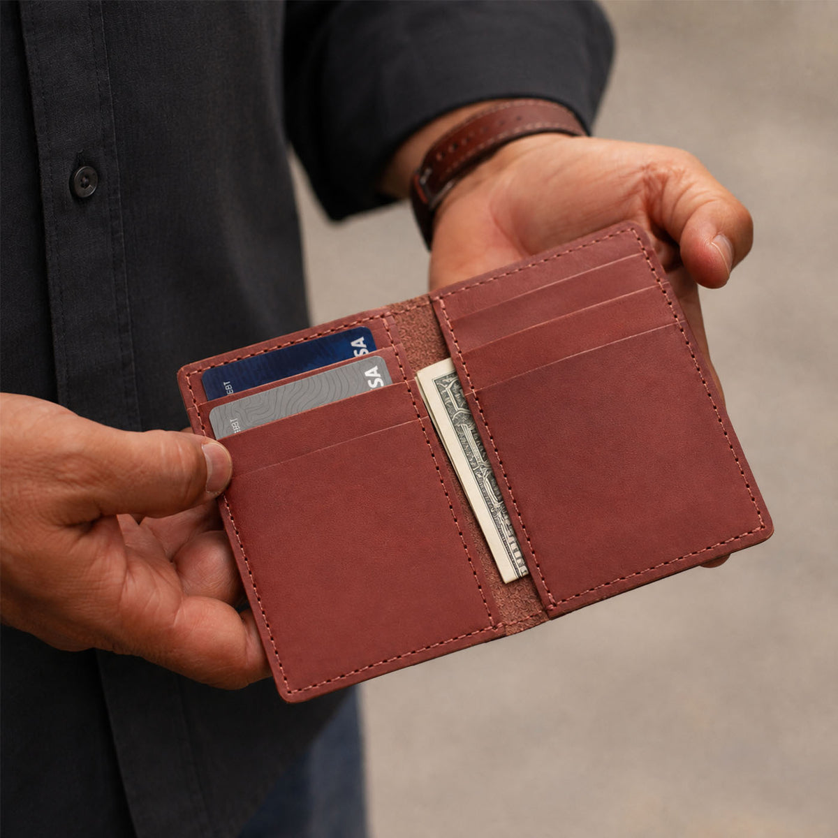 Marrone | A close-up shot of hands holding an open card holder against a neutral background 
