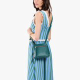 Sea Glass Small | Model carrying compact leather bag with top zipper, front zipper pocket, and adjustable crossbody strap