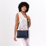 Night Owl Large | A Model holding a zip top crossbody bag with detachable strap
