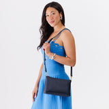 Night Owl Small | A Model holding a zip top crossbody bag with detachable strap
