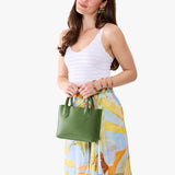 Cactus Small | Model holding a petite tote purse with structured leather handles and crossbody strap