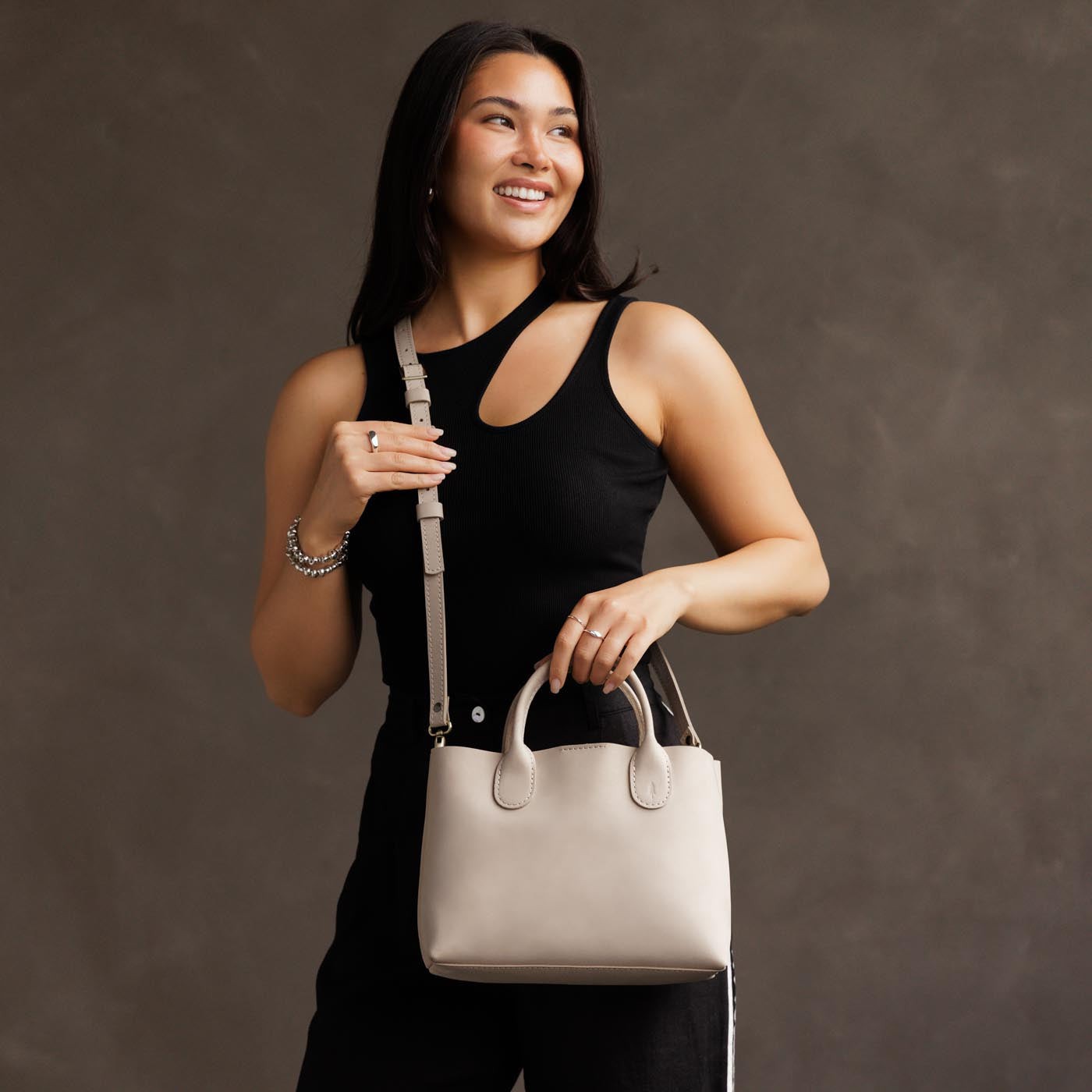 Dragon Bone*Large | Model holding mid-size tote purse with  structured leather handles and crossbody strap