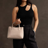 Dragon Bone Large | Model holding mid-size tote purse with  structured leather handles and crossbody strap
