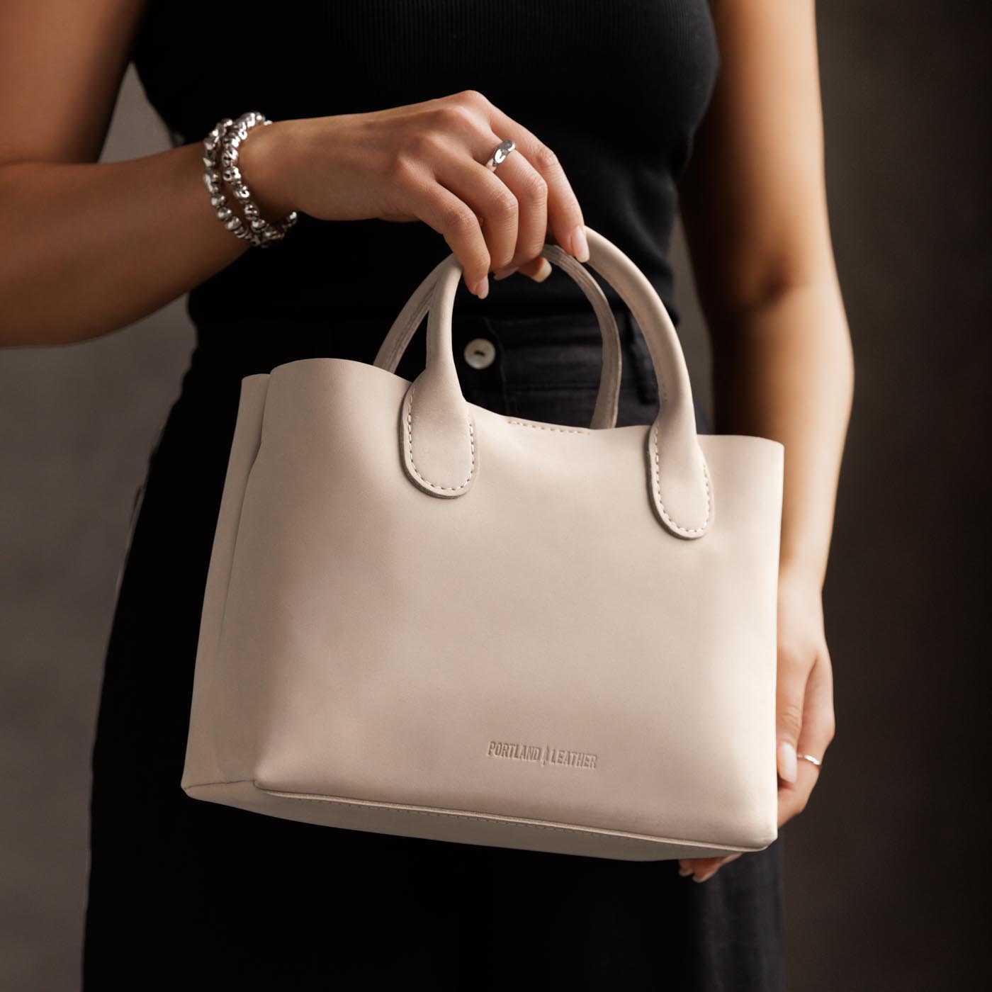 Dragon Bone*Large | Model holding mid-size tote purse with  structured leather handles and crossbody strap