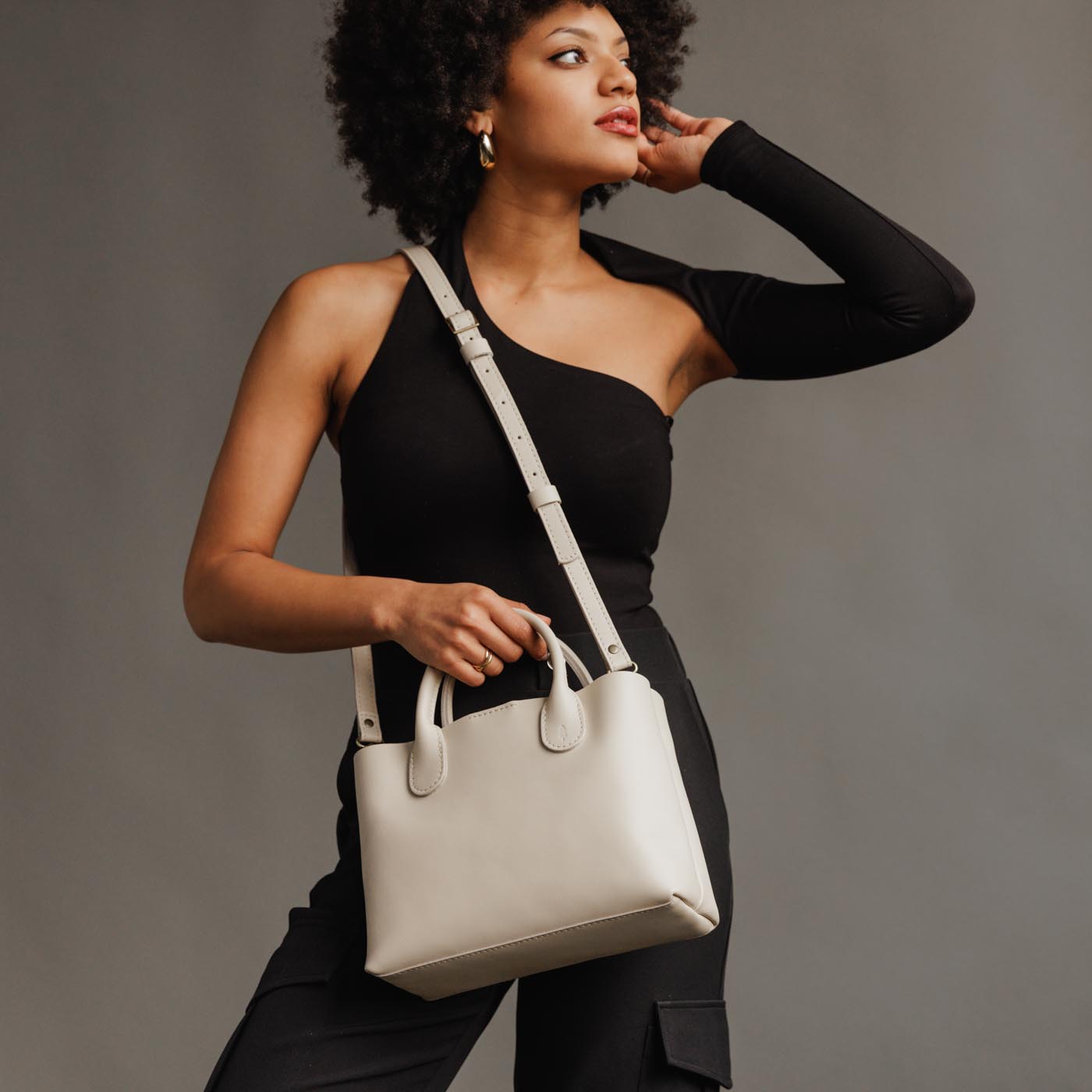 Bone*Large | Model holding mid-size tote purse with  structured leather handles and crossbody strap