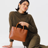 Honey Large | Model holding mid-size tote purse with  structured leather handles and crossbody strap