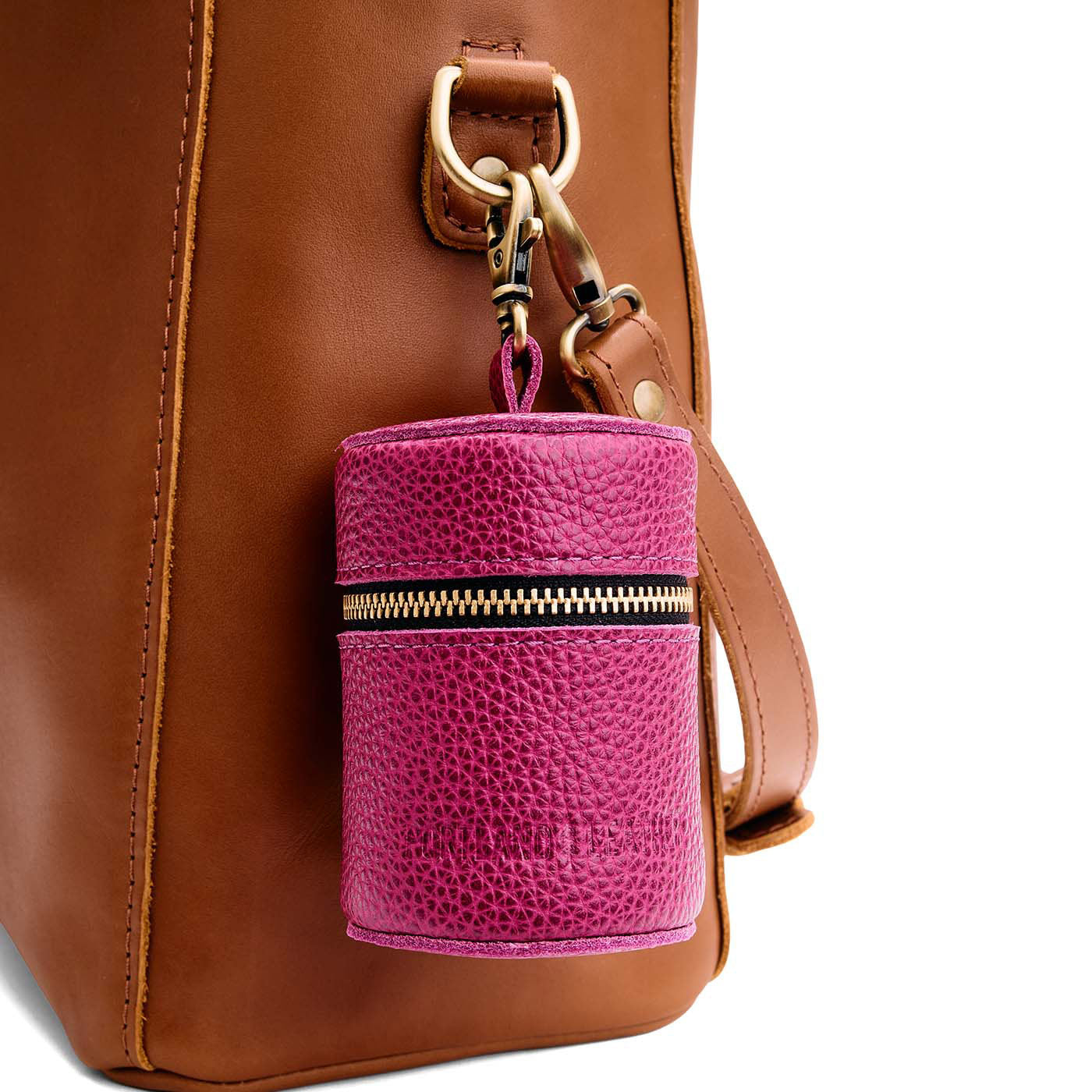 Cosmo | Cylindrical shaped pouch with a gold zipper and swivel lobster claw clasp on a bag