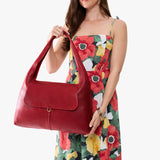 Chili Red Large | A model holding a slouchy triangle shaped shoulder bag with a flap