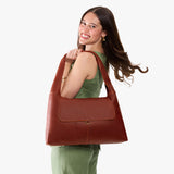 Nutmeg Large | A model holding a slouchy triangle shaped shoulder bag with a flap