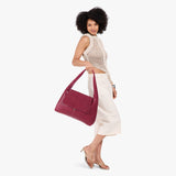 Orchid Large | A model holding a slouchy triangle shaped shoulder bag with a flap