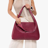 Orchid Large | A model holding a slouchy triangle shaped shoulder bag with a flap