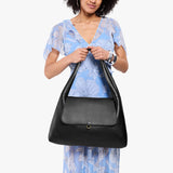 Pebbled--black Large | A model holding a slouchy triangle shaped shoulder bag with a flap