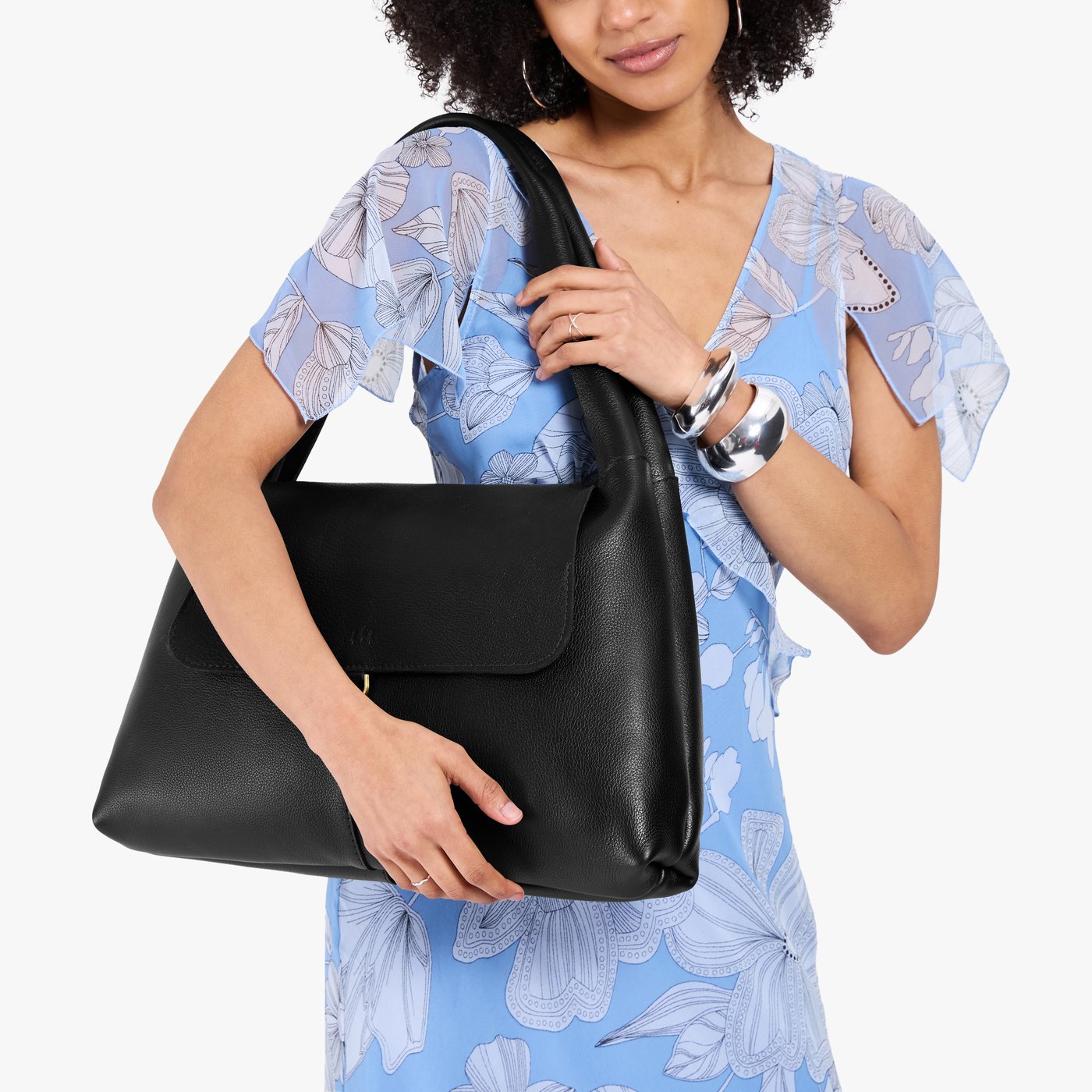 Pebbled--black*Large | A model holding a slouchy triangle shaped shoulder bag with a flap