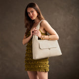 Pebbled Bone Large | A model holding a slouchy triangle shaped shoulder bag with a flap
