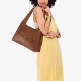 Asheville Medium | A model holding a slouchy triangle shaped shoulder bag with a flap