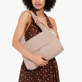 Taupe Medium | A model holding a slouchy triangle shaped shoulder bag with a flap