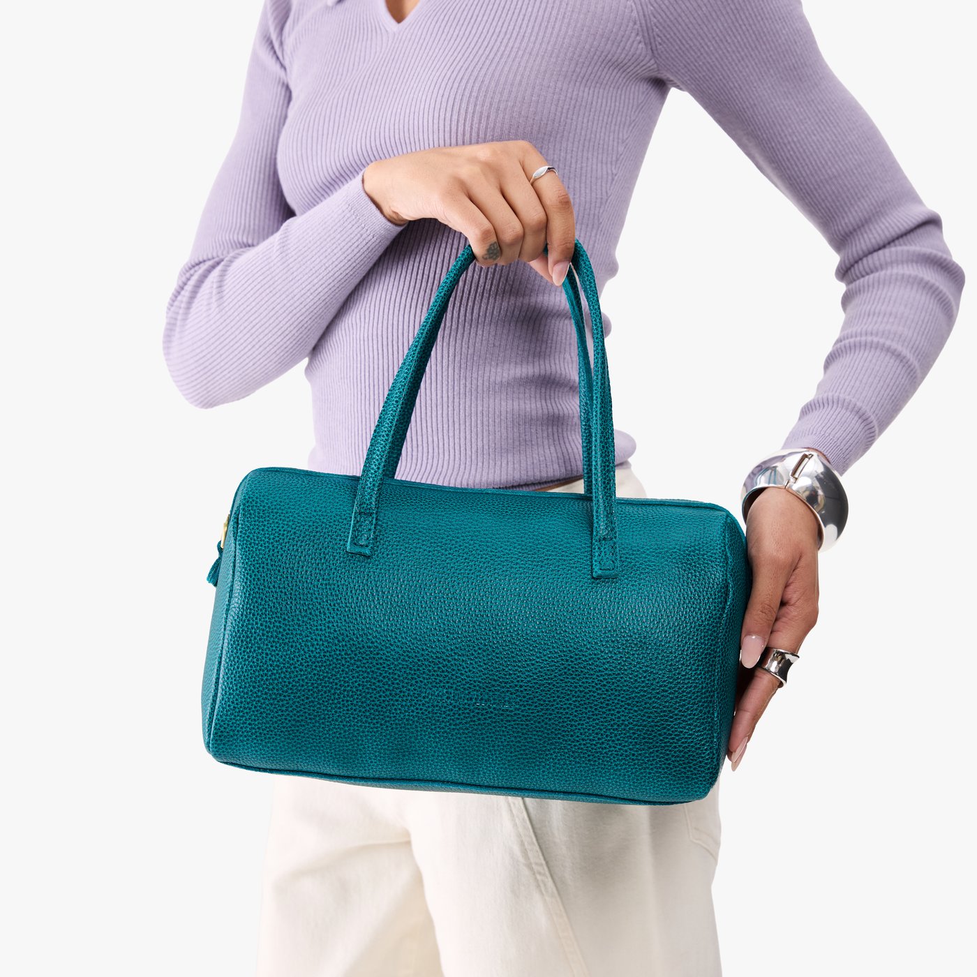 Aquarius*Oversized | Model holding mini duffle shaped handbag with crossbody strap
