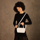 Pebbled Bone Small | Model holding mini duffle shaped handbag with crossbody strap