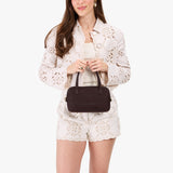 Velvet Brown Small | Model holding mini duffle shaped handbag with crossbody strap