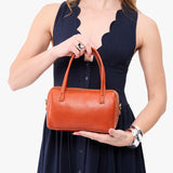 Koi Small | Model holding mini duffle shaped handbag with crossbody strap