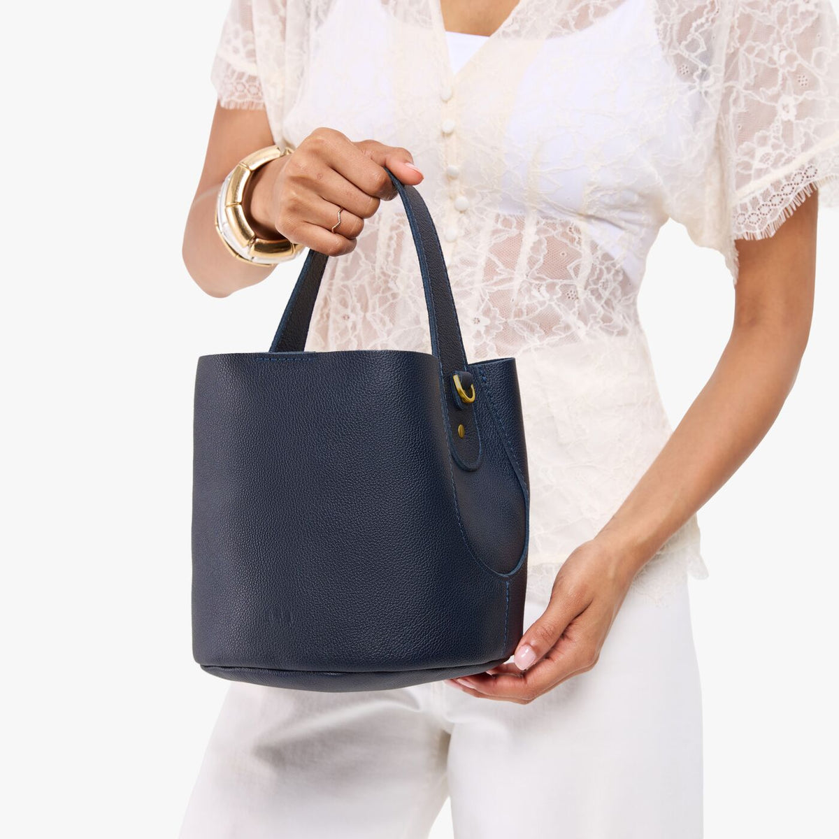 Night Owl*Small | Model carrying symmetrical bucket bag with handle, latch closure, and removable crossbody strap