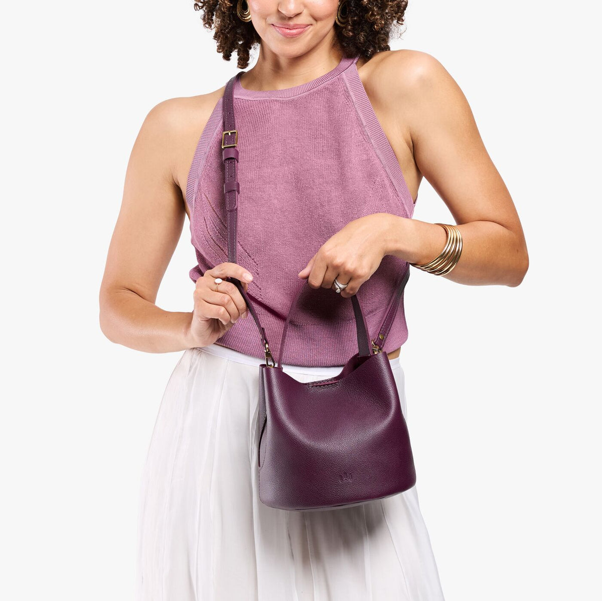 Plum*Small | Model wearing symmetrical bucket bag with handle, latch closure, and removable crossbody strap