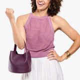 Plum Small | Model carrying symmetrical bucket bag with handle, latch closure, and removable crossbody strap