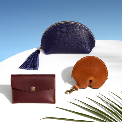 Three leather pouches in blue, brown, and red on a white surface with a blue sky background. featured image