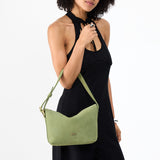 Laurel Small | Model holding a Slouchy Shoulder Bag that has a zipper opening and three metal tree emblems
