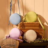 All Variants | Round bags in various colors with a wicker basket on a wooden surface.