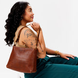Nutmeg Classic | Model carrying triangular shoulder bag with antiqued brass finished hardware