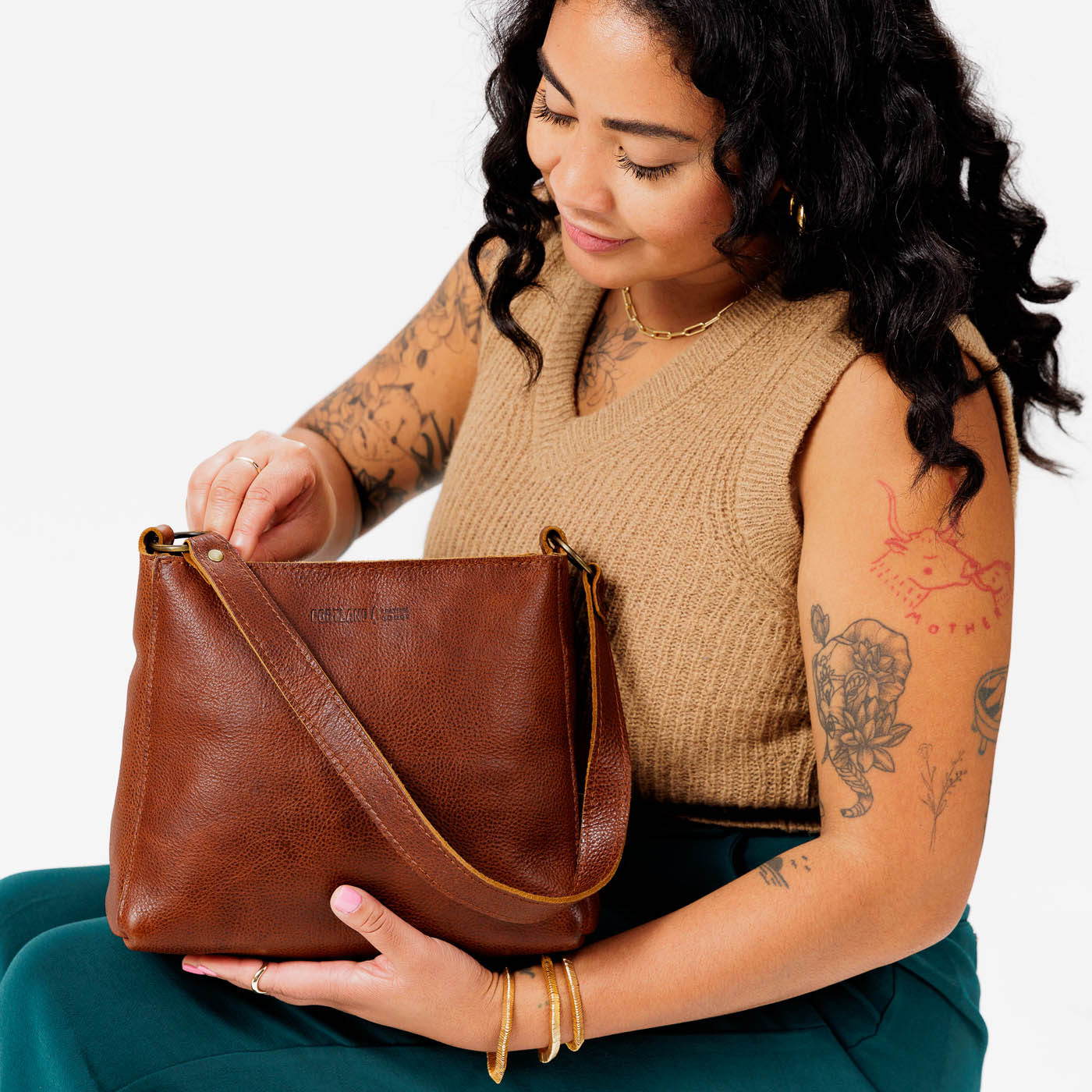 Nutmeg*Classic | Model holding triangular shoulder bag with antiqued brass finished hardware
