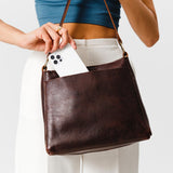 Coldbrew Classic | Model holding leather triangular shoulder bag with zipper top closure and wide shoulder strap